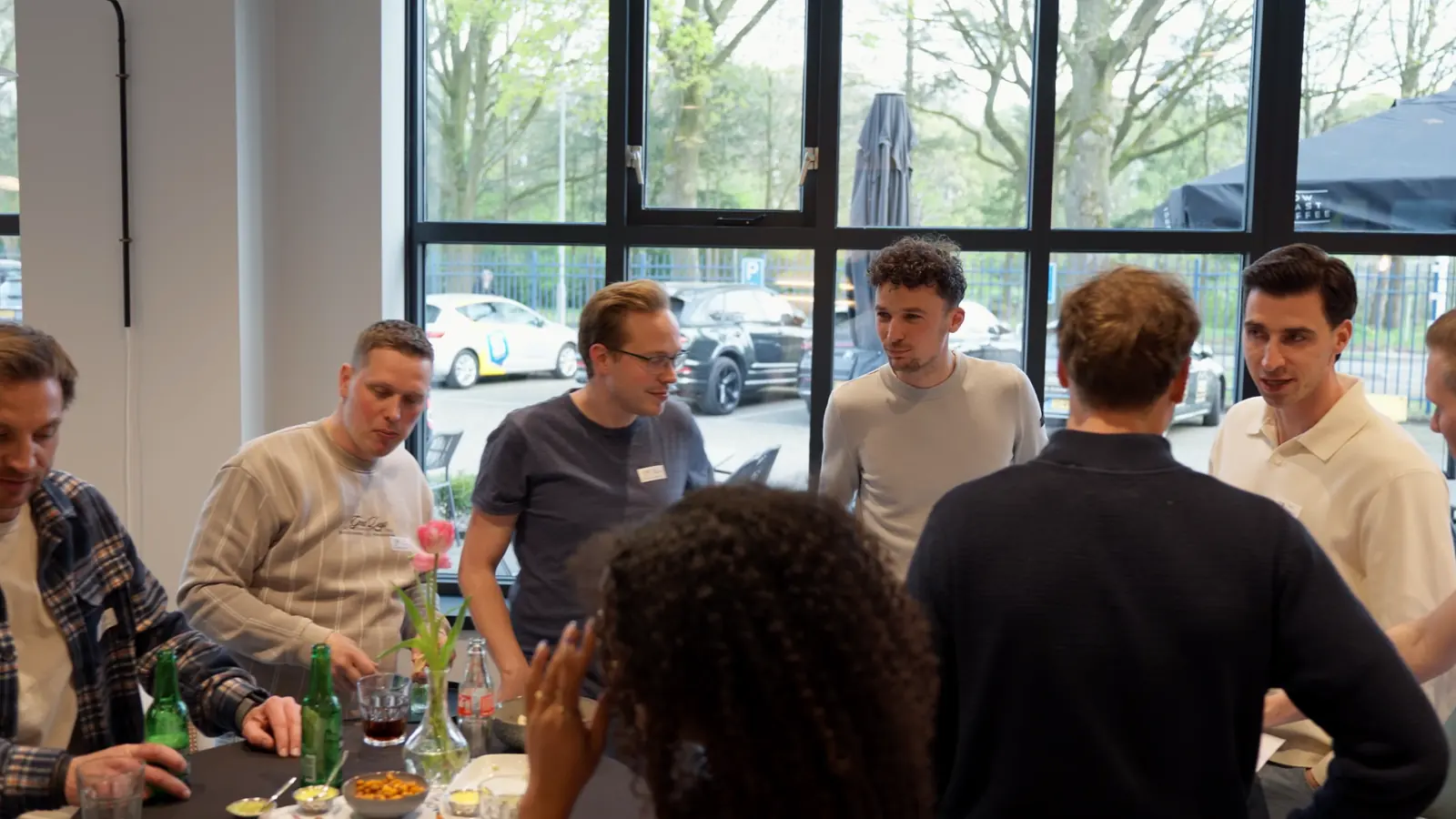 Ondernemers in gesprek aan een statafel bij het raam, tijdens de borrel