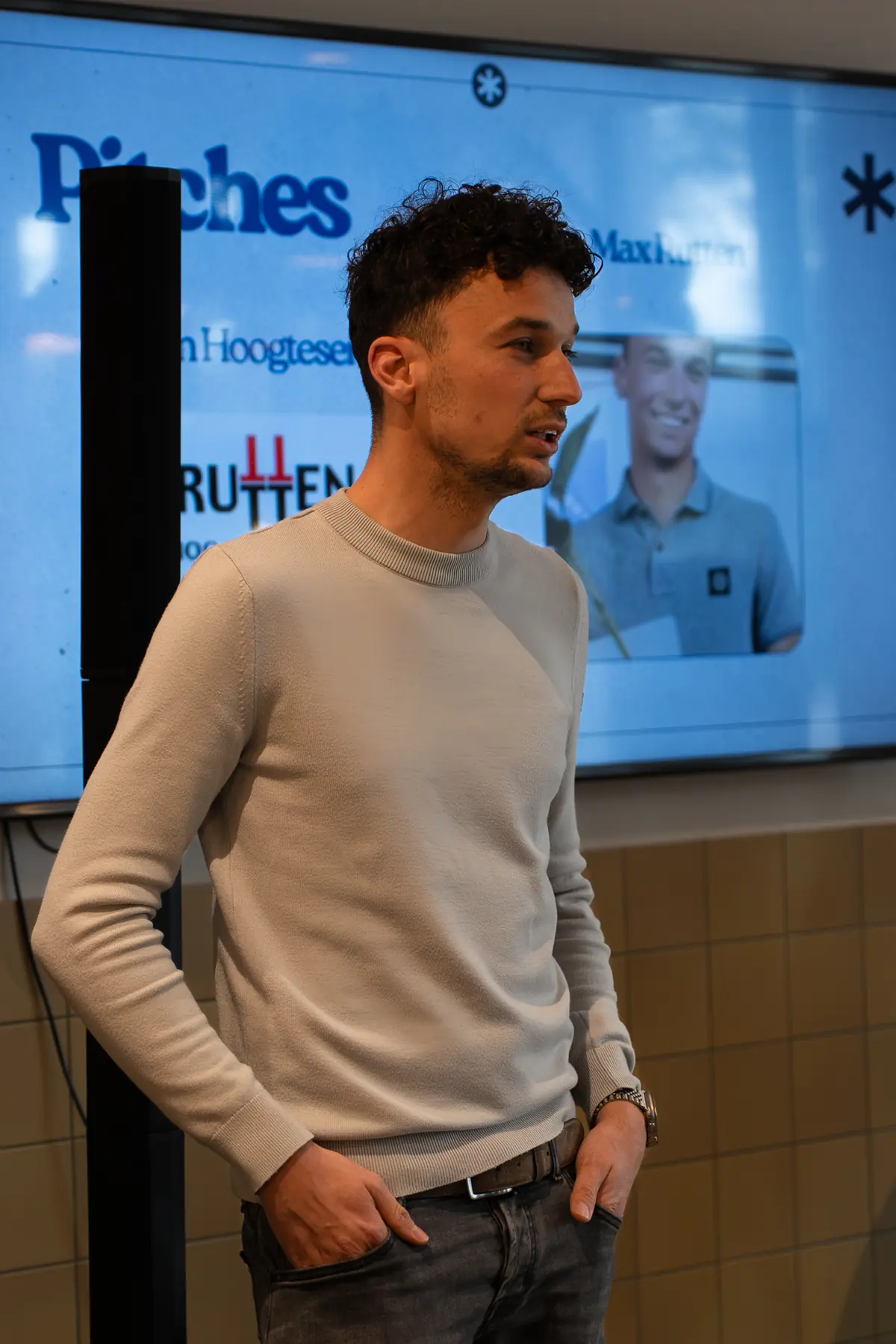 Pitch van een ondernemer, met de naam van het bedrijf op het scherm erachter