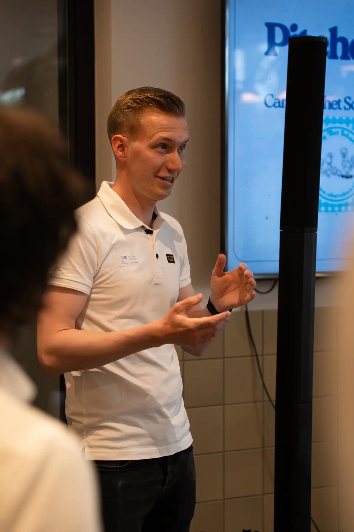 Pitch van een ondernemer in een wit poloshirt, voor het scherm met de pitches
